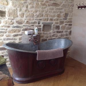 Cette chambre dispose d'une baignoire en bois et d'un mur en pierre. dans l'établissement Au Château, à La Lucerne-dʼOutremer