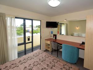 a room with a desk and a bed and a mirror at Bella Vista Motel Mosgiel in Mosgiel