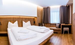 a bedroom with a large bed with white pillows at Hotel Des Alpes in Selva di Val Gardena