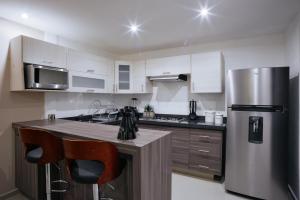 cocina con armarios blancos y nevera de acero inoxidable en Ventura Apartments, en Celaya