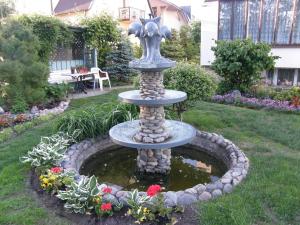 a fountain in the middle of a yard with flowers at Pas Elvyrą in Palanga