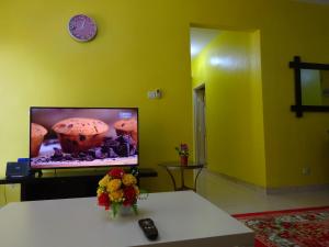 een woonkamer met een tv en een tafel met bloemen bij Al Imam's HOMESTAY Near Sunway Lagoon in Petaling Jaya