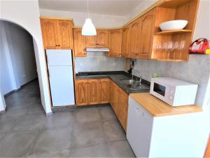 a kitchen with wooden cabinets and a white microwave at C4 Cactus Holiday Homes - Puerto del Rosario in Puerto del Rosario