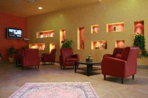 una sala de espera con sillas rojas y TV de pantalla plana. en MARCHESINA RESORT srls, en Teggiano