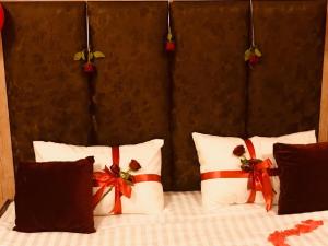 Una cama con almohadas blancas y arcos rojos. en Layali Alandlous Furnished Units en Al Qunfudhah