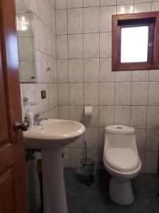 ein Bad mit einem Waschbecken, einem WC und einem Fenster in der Unterkunft Cabaña en Dalcahue in Dalcahue