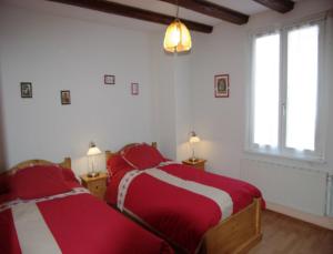 two beds in a bedroom with red and white sheets at Gîte Le Merle 90m2 près de la route des vins in Ammerschwihr