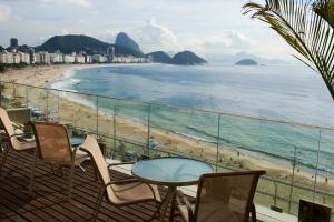 a balcony with a table and chairs and a beach at Studio Copacabana Exclusivo, Na Rua Silva Castro, 4 min da Praia e Metrô, Ganhe 1 ESPUMANTE de boas vindas nas reservas acima de 3 dias, para brindar essa experiência icônica, com Ar e Wi-Fi in Rio de Janeiro