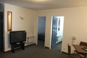 a living room with a television and a room with a bed at ASURE 83 By The Sea Motor Lodge in Lower Hutt