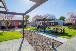 
a patio area with chairs, tables, and benches at Christchurch Park Motel in Christchurch
