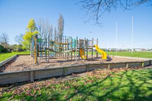 a playground with a yellow slide in a park at Christchurch Park Motel in Christchurch