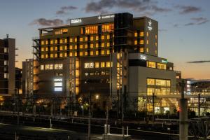 a tall building with lights on in a city at Candeo Hotels Osaka Kishibe in Suita