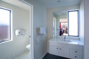 
a bathroom with a sink, mirror, and bathtub at Christchurch Park Motel in Christchurch
