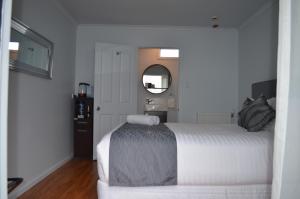 a bedroom with a white bed and a mirror at Tongariro Springs Boutique Suites in National Park