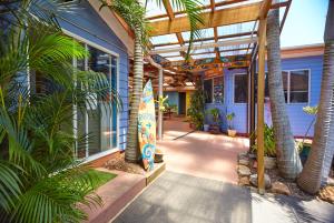 a house with palm trees and a surfboard in a courtyard at Ozzie Pozzie Backpackers - Port Macquarie YHA in Port Macquarie