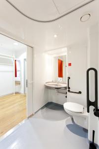 a white bathroom with a toilet and a sink at Just Rest Automatic Hostel in Viljandi
