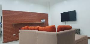 ein Sofa mit orangefarbenen Kissen im Wohnzimmer in der Unterkunft KDC Homes (Gold) in Puerto Princesa