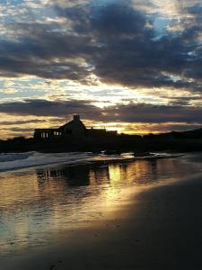 a house on the shore of a beach at sunset at Complejo Los Girasoles in Punta Del Diablo