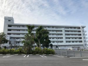a white building with a parking lot in front of it at Eagle Lodge in Chatan