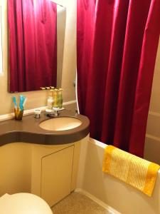 a bathroom with a sink and a red shower curtain at Eagle Lodge in Chatan