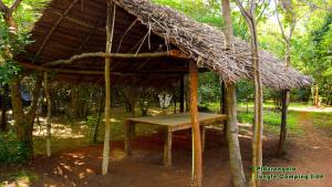 a hut with a table and a grass roof at Sigiri Jungle Camping in Sigiriya