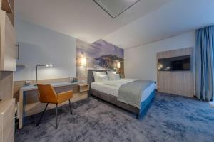 Schlafzimmer mit einem Bett, einem Schreibtisch und einem TV in der Unterkunft Best Western Hotel Wiesbaden in Wiesbaden