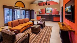 Best Western Executive Inn El Campo في El Campo: غرفة انتظار مع أريكة وطاولة وكراسي