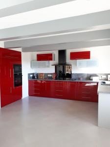 a red kitchen with white floors and red cabinets at La Fenière in Sault-de-Vaucluse