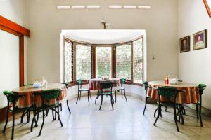- une salle à manger avec des tables, des chaises et des fenêtres dans l'établissement RedDoorz Plus near Brawijaya Museum, à Malang