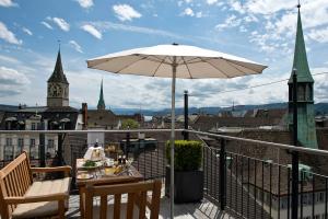 einen Balkon mit einem Sonnenschirm, einem Tisch und Stühlen in der Unterkunft Widder Hotel - Zurichs luxury hideaway in Zürich