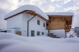 a house with snow on the roof at Appartement Mühltal in Westendorf