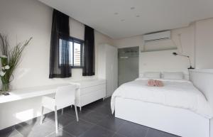 Un dormitorio blanco con una cama y un escritorio. en Luxury Penthouse 2 bed near Rothchild, en Tel Aviv