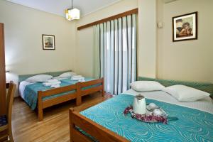 a bedroom with two beds and a table with a plate on it at Hotel Loutraki in Loutraki
