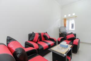 a living room with red and black couches and a table at RedDoorz near Universitas Palangkaraya in Palangkaraya