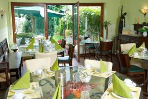 a restaurant with tables and chairs with green napkins at Hotel Sonnenhof in Hanau am Main