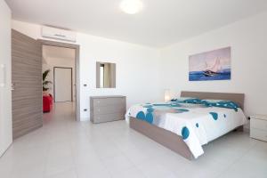 a white bedroom with a large bed with blue pillows at Il Gabbiano - Case Vacanze in Capo dʼOrlando