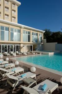 a swimming pool with chairs and a building at BE Resort Mactan in Mactan