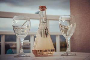 two wine glasses and a bottle on a table at Studio Silvana & Room Renata in Lumbarda