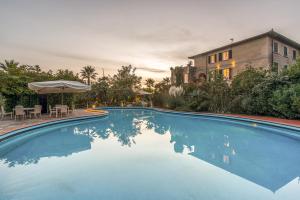 a swimming pool with a table and an umbrella at Hotel Villa Maremonti in Marina di Massa