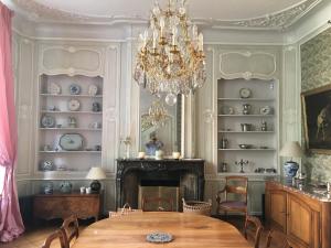 uma sala de jantar com uma mesa e um lustre em Entre Cour et Jardin em Arras