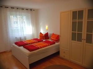 Schlafzimmer mit einem Bett mit roten und orangefarbenen Kissen in der Unterkunft Freiburg Apartment in Freiburg im Breisgau