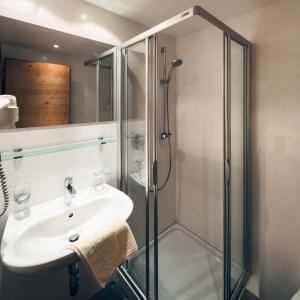 ein Bad mit einem Waschbecken und einer Dusche in der Unterkunft Hotel Barbara in Serfaus