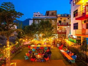 a group of people sitting at tables in a courtyard at night at goSTOPS Rishikesh, Tapovan in Rishīkesh