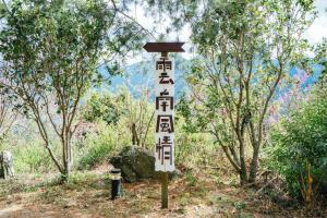 um sinal no meio de uma floresta com árvores em Yunnan Homestaty em Ren'ai