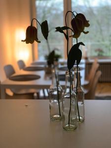 Tres jarrones de cristal con flores en una mesa. en Ferienwohnung Parkblick en Bremen