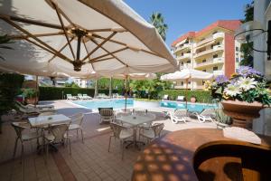 a patio with tables and umbrellas next to a pool at Residence Torre Del Mar in Alba Adriatica