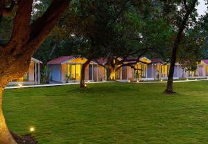 a building with trees in a grassy yard at Blu Resorts in Vagator