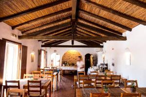 a restaurant with tables and chairs and a person in the background at Herdade Do Freixial - Turismo Rural in Vila Nova de Milfontes