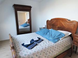 Gite l'Etoile du Berger في La Bohalle: غرفة نوم مع سرير ووسائد زرقاء ومرآة