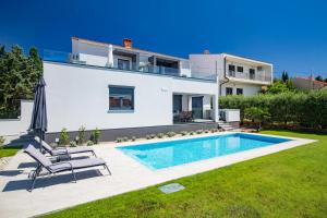 a villa with a swimming pool in front of a house at Bonihome Apartments in Punat